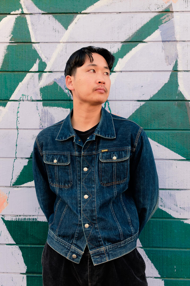 Untitled Man standing in front of green brick wall with painted flowers